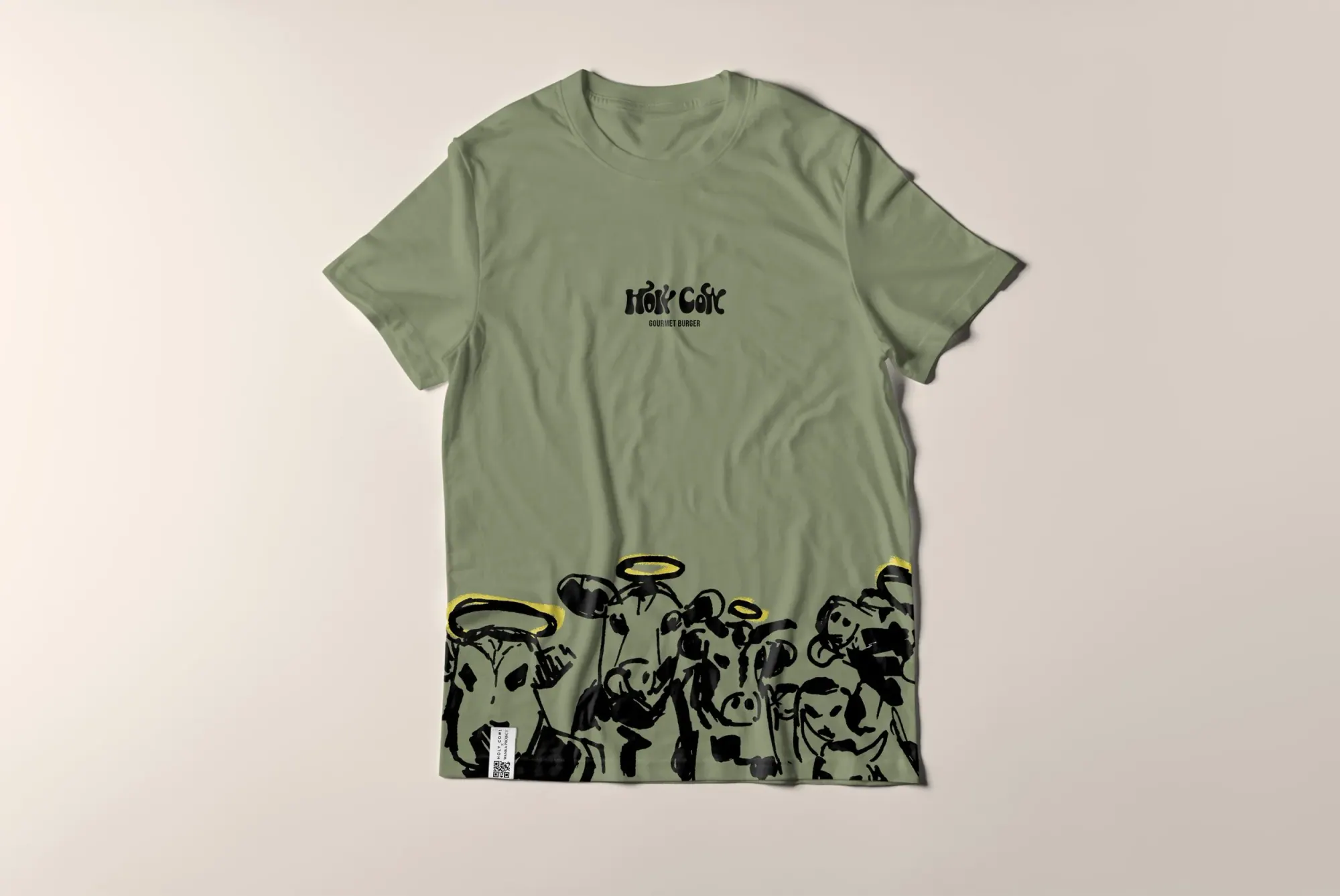 T-shirt vert avec illustration de plusieurs animaux avec des halos dorés au bas du vêtement, et texte en haut "HOT COT" avec sous-texte "GOURMET BURGER".