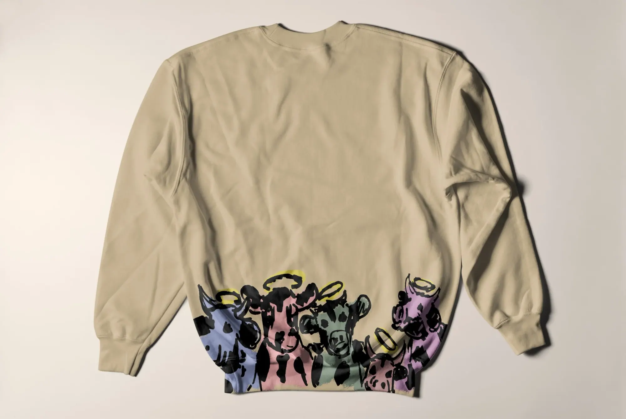 Sweat-shirt beige avec une impression de plusieurs vaches colorées au bas.