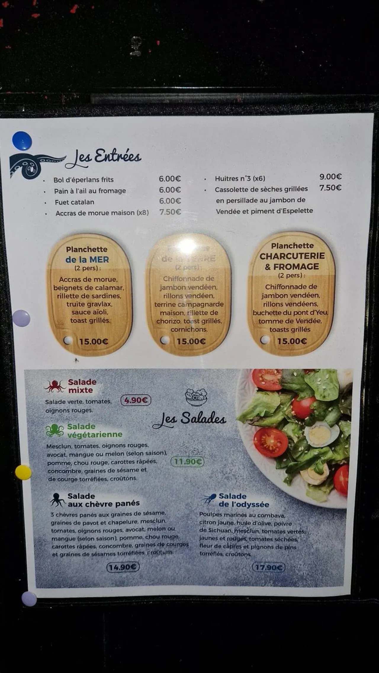 Menu de restaurant avec différentes entrées, salades et plateaux de charcuterie et fromages.