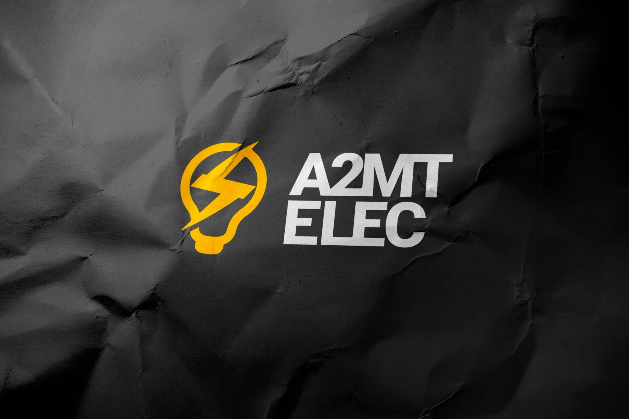 Logo de l'électricien A2MT ELEC, avec une ampoule stylisée en jaune contenant un éclair, sur un fond noir texturé.