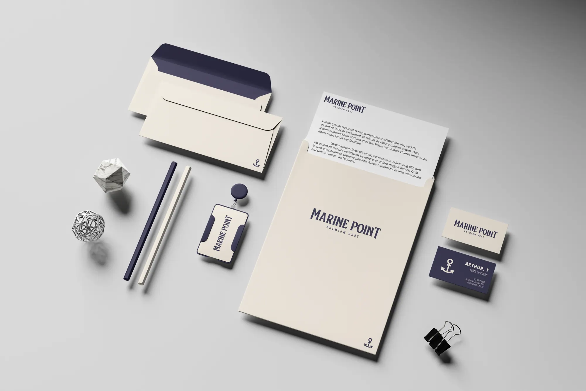 Papeterie maritime blanche et bleue avec enveloppes, cartes de visite, crayon, clef USB, et papiers avec logo "Marine Point" sur une surface grise.